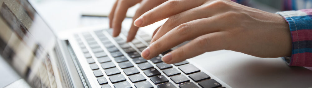 Cropped View of Hands Typing on Laptop