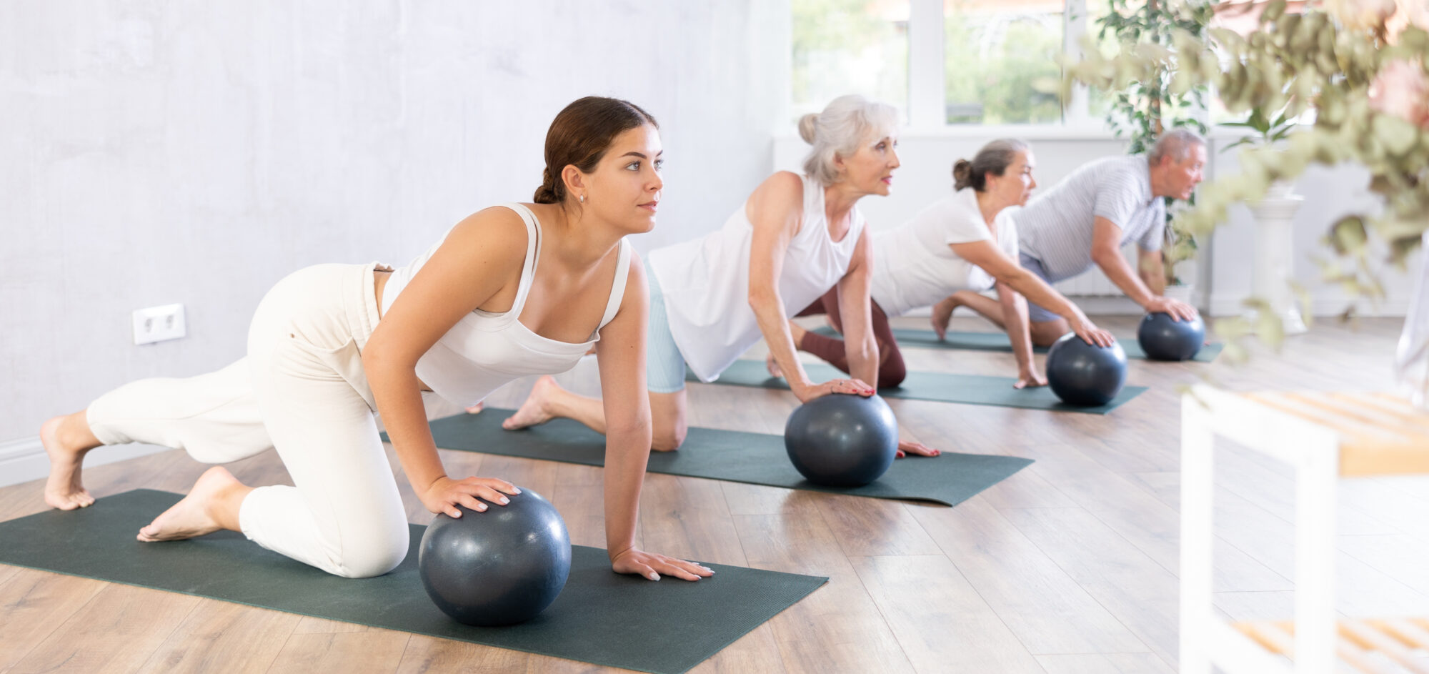 Group of mature active people doing soft ball exercises during group pilates class in fitness studio